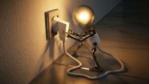 Lightbulb with robotic arms unplugging from socket - energy efficiency